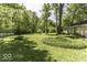 A sprawling backyard with lush green grass and mature trees, partially enclosed by a white picket fence at 6204 S Madison Ave, Indianapolis, IN 46227