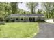 Charming single-story home featuring stone accents, a well-manicured lawn, and a paved driveway surrounded by mature trees at 6204 S Madison Ave, Indianapolis, IN 46227