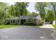 Charming single-story home featuring a stone facade, mature trees, and a spacious asphalt driveway at 6204 S Madison Ave, Indianapolis, IN 46227