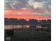Stunning sunset over a serene pond in a residential community, captured behind a wrought iron fence at 6615 Aberdeen Dr, McCordsville, IN 46055