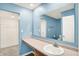 Blue bathroom showcasing a large mirror, sink, and walk-in closet at 6895 Honeysuckle Way, Pendleton, IN 46064