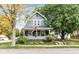 Charming two-story home featuring a welcoming front porch, mature trees, and a well-manicured lawn and garden at 117 N Leland St, Fortville, IN 46040