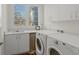 Bright laundry room featuring white cabinets, countertop, sink, and modern Whirlpool washer and dryer set under a window at 12561 Marina View Dr, Indianapolis, IN 46256