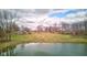 Aerial view of pond featuring a large grassy yard, trees, and surrounding homes at 15123 E 196Th St, Noblesville, IN 46060