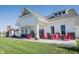 Stunning white farmhouse-style community clubhouse with inviting red Adirondack chairs on the welcoming front porch at 15304 Fairlands Dr, Westfield, IN 46074