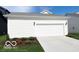 A two-car garage, with a white door and surrounded by a well maintained landscape at 15304 Fairlands Dr, Westfield, IN 46074