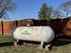 The backyard includes a large propane tank, a wooden fence, and large mature trees at 204 W Pullman St, Waldron, IN 46182