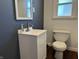 Bathroom featuring a white vanity, toilet, and square mirror with blue accent wall at 204 W Pullman St, Waldron, IN 46182