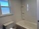 Bathroom showcasing a white bathtub, toilet, vinyl walls and privacy window at 204 W Pullman St, Waldron, IN 46182