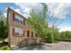 Well-kept brick townhome with red shutters, complemented by a mature tree and landscaping at 3052 Skylar Ln, Indianapolis, IN 46208