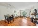 Bright living room with a dining table, wood floors, stylish seating, and a large window overlooking the outdoors at 3052 Skylar Ln, Indianapolis, IN 46208
