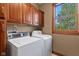 Cozy laundry room featuring a washer, dryer, wood cabinetry, and a window providing natural light at 3608 Olive Branch Rd, Greenwood, IN 46143