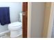 Toilet in tiled bathroom with a blue towel, brown wood door, and a grey wall at 5582 E State Road 144, Mooresville, IN 46158