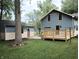 View of the backyard featuring a well-maintained lawn, a wooden deck, and a detached shed matching the house's exterior at 5603 S Randolph St, Indianapolis, IN 46227
