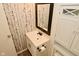 Cozy bathroom with a modern vanity, decorative mirror, and patterned wallpaper, creating a stylish, compact space at 5909 Furnas Rd, Indianapolis, IN 46221
