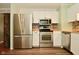 Stainless steel refrigerator and range with white cabinets and butcher block counters in the kitchen at 5909 Furnas Rd, Indianapolis, IN 46221