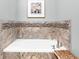 A pristine white tub is surrounded by decorative stone and tile in this relaxing and modern bathroom at 6980 N Pennsylvania St, Indianapolis, IN 46220