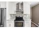 Kitchen featuring an island range and hood with white cabinets and mosaic backsplash at 6980 N Pennsylvania St, Indianapolis, IN 46220