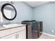 A well-lit laundry room with modern washer and dryer, vanity and granite countertop at 6980 N Pennsylvania St, Indianapolis, IN 46220