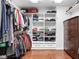 Organized walk-in closet with custom shelving, hanging rods, and a wooden dresser on gleaming hardwood floors at 6980 N Pennsylvania St, Indianapolis, IN 46220