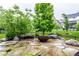 Stone patio features an outdoor fire pit, beautiful landscaping, and lush green lawn at 12167 Ams Run, Carmel, IN 46032