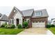 Beautiful brick home with stone accents, lush lawn, and a spacious three-car garage and driveway at 12167 Ams Run, Carmel, IN 46032