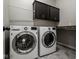 Laundry room with modern washer and dryer units, dark cabinets, and countertop space at 12167 Ams Run, Carmel, IN 46032