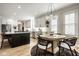 Well-lit kitchen with white cabinetry, island with barstool seating, and an adjacent dining space at 13018 Deerstyne Green St, Carmel, IN 46032