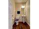 Cozy half bathroom with wood floors, a pedestal sink, and a toilet with a purple seat cover at 15453 Old Pond Cir, Noblesville, IN 46060