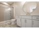 This bathroom features white cabinets, modern round mirror, tiled floors, and shower with glass door at 3787 Cherwell Dr, Zionsville, IN 46077