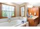 Bright bathroom featuring a large soaking tub, dual windows, and wood cabinets with a white countertop at 4590 Turkey Track Rd, Martinsville, IN 46151