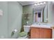 Powder room with light green walls, sink and toilet with wood cabinets and a decorative mirror at 6843 Long Run Dr, Indianapolis, IN 46268
