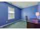 This bedroom features a blue painted walls, a desk, a window, and soft carpeting at 6843 Long Run Dr, Indianapolis, IN 46268