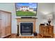 Fireplace with a TV above displaying an exterior shot of the house, flanked by wooden cabinets and elegant lamps at 6843 Long Run Dr, Indianapolis, IN 46268