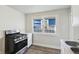 Kitchen area featuring a stainless steel stove, white cabinets, and a window overlooking the yard at 741 N Linwood Ave, Indianapolis, IN 46201