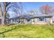 Charming stone-clad ranch home features a well-maintained lawn, blue shutters and mature shade trees at 7816 E St Joseph St, Indianapolis, IN 46219