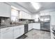Bright kitchen featuring white cabinets, stainless steel appliances and gray tile flooring at 7816 E St Joseph St, Indianapolis, IN 46219