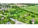 Aerial view displays a charming property with lush green field, barn, and a pond at 905 S Maple St, Fortville, IN 46040