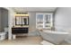 A modern bathroom provides a soaking tub with a window and a dark vanity at 10145 Northwind Dr, Indianapolis, IN 46256