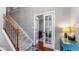 Open hallway with hardwood floors and a view into the home office through glass paneled doors at 10145 Northwind Dr, Indianapolis, IN 46256