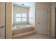 Bathroom featuring a tiled, raised soaking tub with gold fixtures and a window at 12348 Seaway Cir, Indianapolis, IN 46236