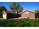 Charming brick home featuring a detached garage, lush green lawn, and a private patio at 1509 E Centennial Ave, Muncie, IN 47303