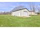 Angled view of the detached garage shows a standard door and a roll-up door on a large manicured lawn at 2274 W Huntsville Rd, Pendleton, IN 46064