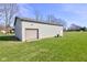 Angle view of the detached garage with two roll-up doors and a door with a concrete drive and green grass at 2274 W Huntsville Rd, Pendleton, IN 46064