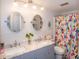Bright bathroom featuring a double vanity with marble countertops, round mirrors, and a colorful shower curtain at 3335 Woodcrest Ct, Columbus, IN 47203