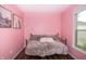 Cozy bedroom featuring pink walls, wood floors, artwork, and a comfortable twin sized day bed by a bright window at 3335 Woodcrest Ct, Columbus, IN 47203