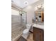 Bright bathroom featuring white tile shower, dark vanity, and stone-style flooring at 4491 N 75 W, Franklin, IN 46184