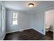 Bedroom with dark wood-look flooring, two windows, and a view into an adjacent bathroom at 611 Della Rd, Columbus, IN 47203
