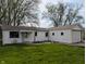 Charming one-story home with white siding, an attached garage, and a spacious front yard with dandelions at 611 Della Rd, Columbus, IN 47203