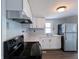 Well-lit kitchen with white cabinets, stainless steel refrigerator, and black appliances at 611 Della Rd, Columbus, IN 47203